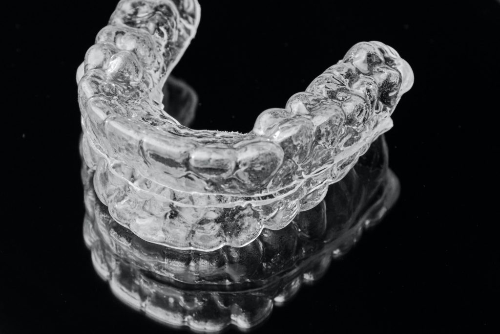 Invisible transparent dental removable braces on the black background. Orthodontic appliance for